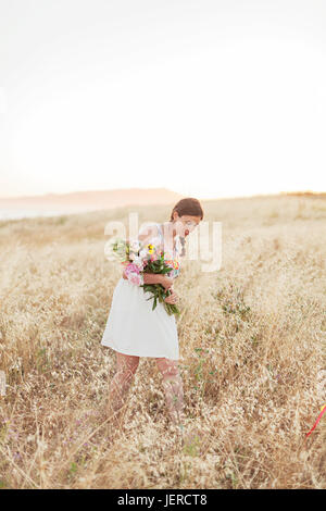 Donna con fiori a piedi in Prato Foto Stock