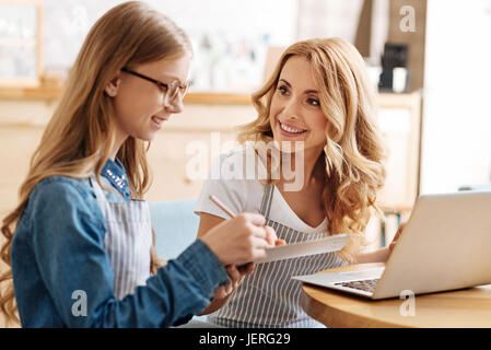 Felice madre guardando la sua figlia di lavoro con orgoglio Foto Stock