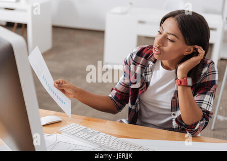 Gravi di lavoro duro donna che guarda il documento Foto Stock