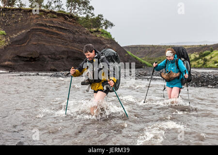 Gli escursionisti che attraversano il fiume Pronga in Heavy Rain vicino Thorsmork sul Laugavegur Trail, Islanda. Foto Stock