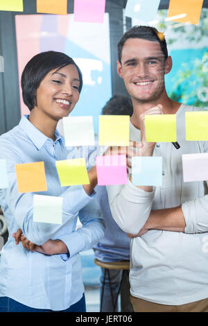 I colleghi sorridente guardando sticky notes Foto Stock