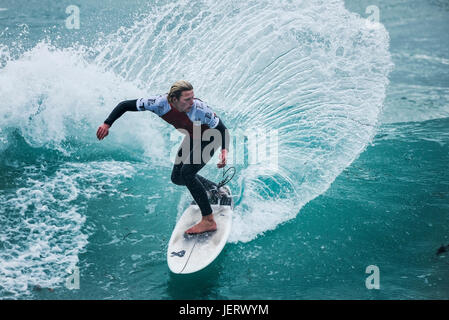 Navigare in UK. Spettacolare azione di surf come un surfista cavalca un onda in un concorso a Fistral Beach in Newquay Cornwall, Foto Stock