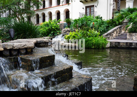 Una cascata lungo la struttura Riverwalk ombreggiata in San Antonio Texas. Foto Stock