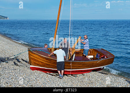 Gli uomini rigging imbarcazione (lugger) sulla spiaggia, birra, Devon, Inghilterra, Regno Unito Foto Stock