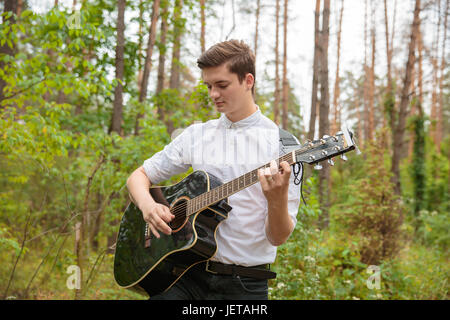 Un uomo è di suonare una chitarra in corrispondenza di una parte esterna Foto Stock