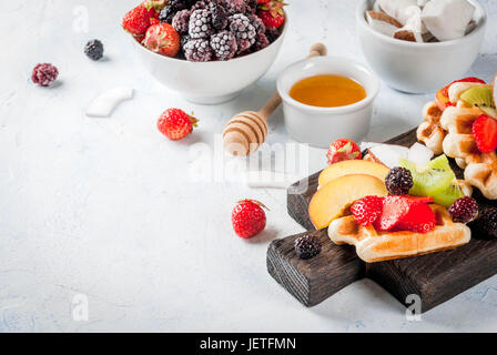 La prima colazione. In casa fresco morbido belga di wafer con miele, frutta, bacche - peach, more, lamponi e fragole, noce di cocco, anacardi, st Foto Stock