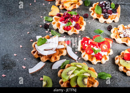 Set di fresco morbido belga di wafer con diversi condimenti - peach, more, lamponi e fragole, noce di cocco, anacardi, fragole e menta. Nero Foto Stock