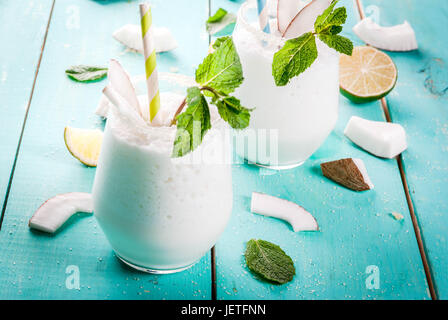 Estate ristoro bevande, cocktail. Congelati mojito di noce di cocco con lime e foglie di menta. La pina colada. Di una luce blu verde tavolo in legno con ingredienti. Copia Foto Stock