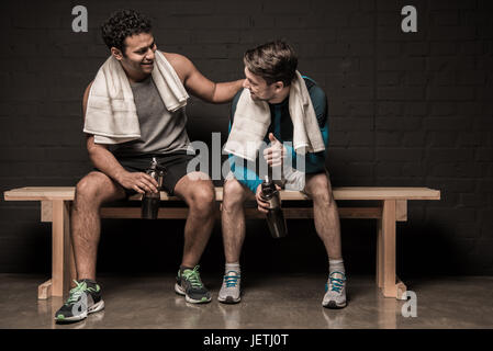 Belli gli atleti maschili in appoggio e conversare in palestra spogliatoi Foto Stock