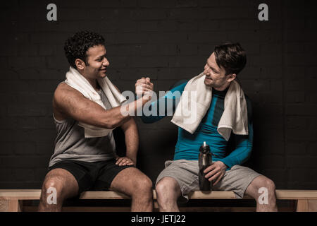 Belli gli atleti maschili in appoggio e conversare in palestra spogliatoi Foto Stock