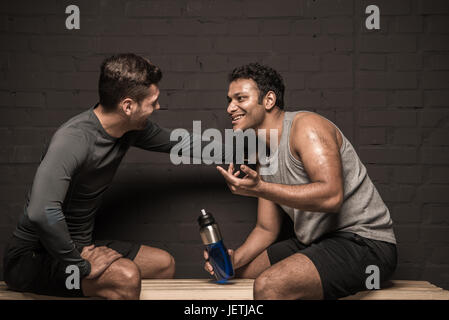 Belli gli atleti maschili in appoggio e conversare in palestra spogliatoi Foto Stock