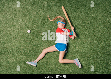 Vista superiore della bambina fingendo a giocare a baseball su erba, atletica concetto per bambini Foto Stock