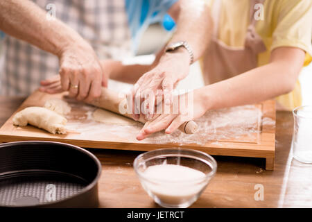 Nipote e nonno di cottura e rendendo la pasta per i biscotti con utensili da cucina al tavolo da cucina, cucina nel concetto di cucina Foto Stock