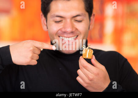 QUITO, ECUADOR- 17 ottobre, 2015: Close up di un sorridente giovane tenendo in mano un dono d'oro presente. Foto Stock