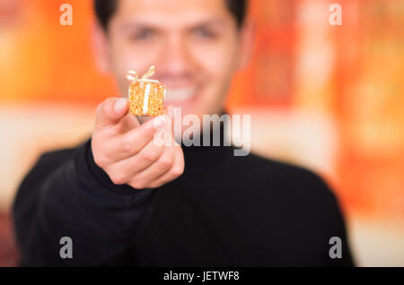 QUITO, ECUADOR- 17 ottobre, 2015: Close up di un sorridente giovane tenendo in mano un dono d'oro presente. Foto Stock