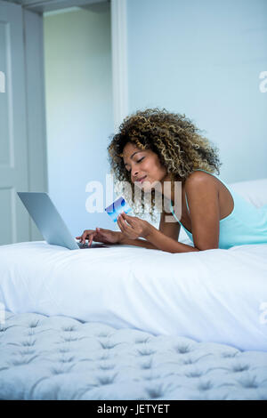 Giovane donna facendo shopping online su laptop Foto Stock