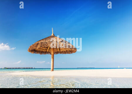 Sandbank tropicale isola con ombrellone. Oceano Indiano, Maldive. Blu cielo soleggiato Foto Stock
