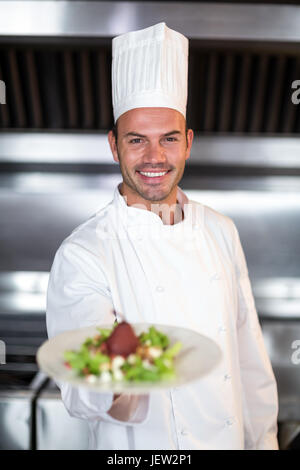 Ritratto di sorridente chef maschio tenendo la piastra Foto Stock