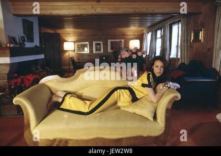 Modello americano Marisa Berenson, in posa di un giallo pigiami di seta disegnato da Valentino. Ella venne a pochi giorni al conduttore austriaco Herbert von Karajan's chalet in Saint-Moritz. Marzo 1974 Photo Michael Holtz Foto Stock