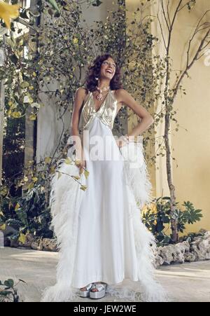 Modello americano Marisa Berenson, ponendo in bianco e oro vestito disegnato da Loris Azzaro. Ottobre 1973 Photo Michael Holtz Foto Stock