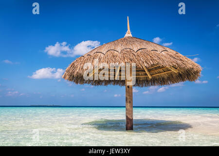 Sandbank tropicale isola con ombrellone. Oceano Indiano, Maldive. Blu cielo soleggiato Foto Stock