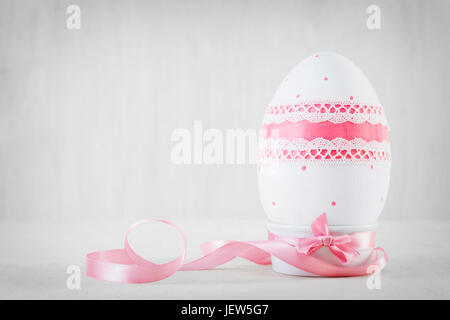 Pasqua singolo uovo fatta a mano in legno tavolo bianco. Decoupage tecnica, toni pastello Foto Stock