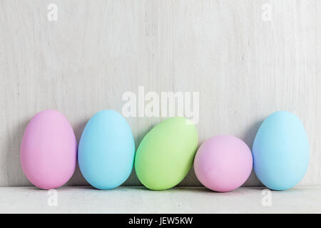 Pastello uova di Pasqua giacente su legno tavolo bianco. Decorazioni tradizionali Foto Stock