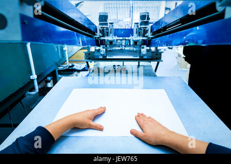 Lavoratore Prepara stampa screening macchina di metallo. Stampante industriale. Fabbricazione di lavoro. La prospettiva in prima persona. Foto Stock