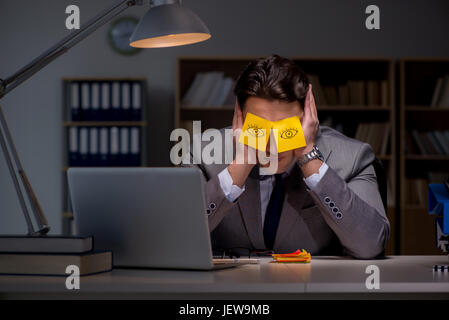 Uomo d'affari che soggiornano in ritardo per ordinare le priorità Foto Stock