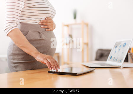 Piacevole donna incinta utilizzando una compressa Foto Stock