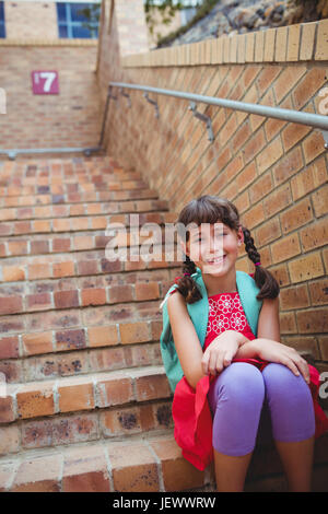 Sorridente schoolgirl seduto in scale Foto Stock