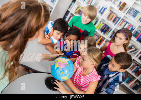 Insegnanti e alunni guardando un mappamondo Foto Stock