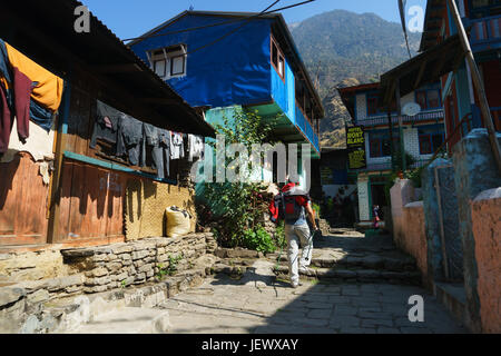 Trekker attraversando il villaggio di jagat sul circuito di Annapurna, Nepal. Foto Stock