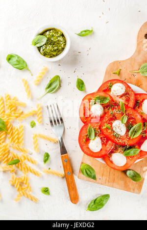 Il cibo italiano. Cena a molla per una persona. Insalata caprese - pomodori, mozzarella, fresca e le erbe aromatiche essiccate, basilico pesto e pasta per c Foto Stock