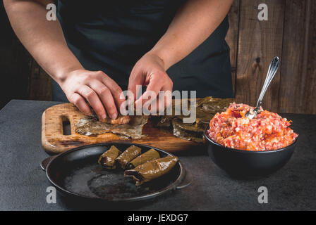 Orientale (Armeno, bagno turco) la tradizionale cucina nazionale. Cibo vegan. Persona nel telaio è in preparazione un dolma - di carne con verdure, avvolto in uva l Foto Stock