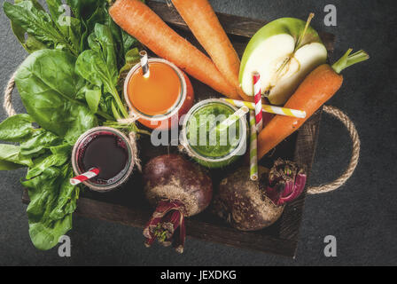 Dieta vegana cibo. Detox bevande. Succhi di frutta freschi e spuntini dalle verdure: barbabietole, carote, spinaci, cetriolo, apple. Sulla pietra scura backgrou Foto Stock