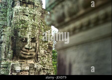 Facce di pietra scolpita in le antiche rovine del tempio Bayon. Foto Stock