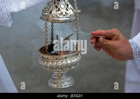 Chierichetto guardando con un cucchiaio d'argento incenso in un incensiere durante una processione della Settimana Santa in Andalusia, Spagna Foto Stock