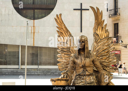 Barcellona, Spagna - 25 Maggio 2017: Street attrice vestito come un angelo dorato sulle Ramblas con una chiesa in background in Barcellona, Spagna. Foto Stock