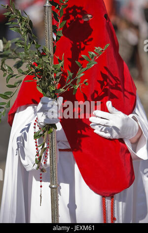 Penitente con un crosier portati di rami di olivo durante una processione della settimana santa domenica delle Palme, Spagna Foto Stock