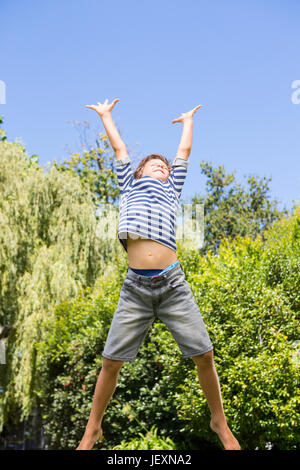 Carino boy jumping con bracci sollevati Foto Stock