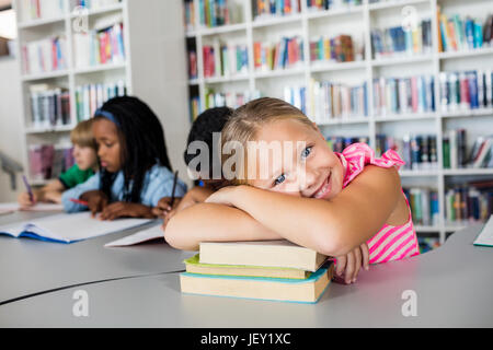 Bambina che pongono il braccio incrociati a scrivania Foto Stock