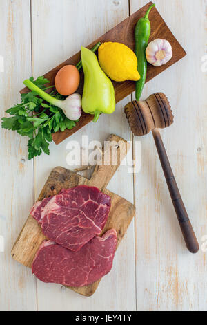 Carne di manzo crudo per schnitzel e le verdure sul piatto di legno. Vista da sopra. Foto Stock