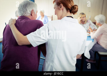 Un infermiere che assiste un senior usando un walker Foto Stock