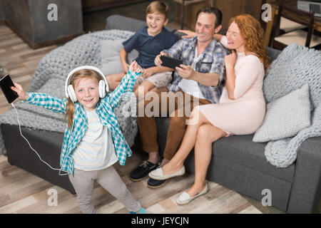 Padre prendendo foto della figlia ascoltando musica in cuffia, sorridenti famiglia seduta sul lettino, i genitori di trascorrere del tempo con i bambini a vivere Ro Foto Stock