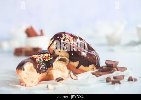 Cioccolato ciambelle vetrata con un pizzico di cannella e su un bianco sullo sfondo di legno Foto Stock