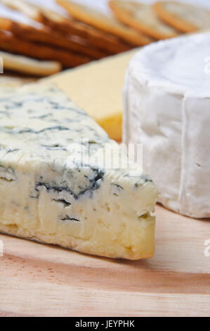 Close up di selezione di formaggi sulla tavola di legno con crackers di messa a fuoco morbida dello sfondo. Focus è sul blu francese di formaggio venato. Foto Stock