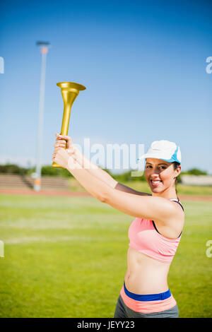 Felice atleta femminile tenendo una torcia di fuoco Foto Stock