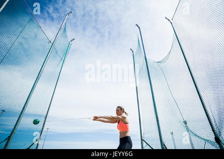 Atleta femminile di eseguire un lancio del martello Foto Stock