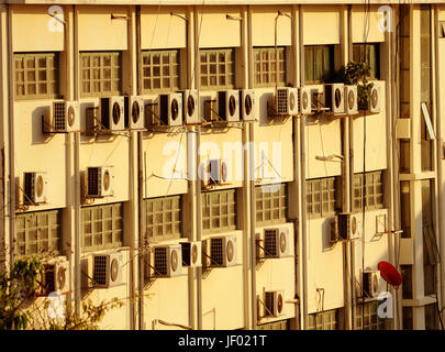 Parete edilizia con numerosi condizionatori e rosso piatti via satellite Foto Stock